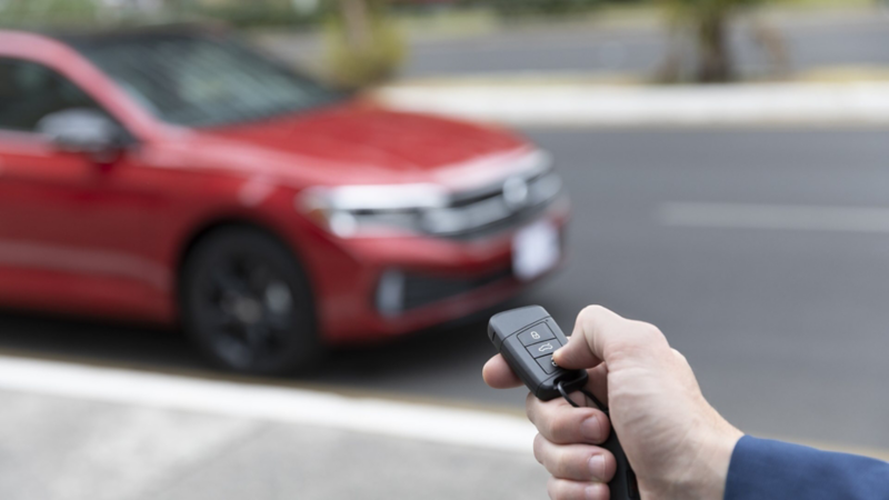 Conductor de Jetta Volkswagen oprime botón del control para abrir o asegurar el vehículo. 