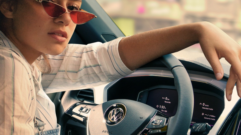 Mujer en interior de auto equipado con sistemas de seguridad Volkswagen ideal para viajar por carretera