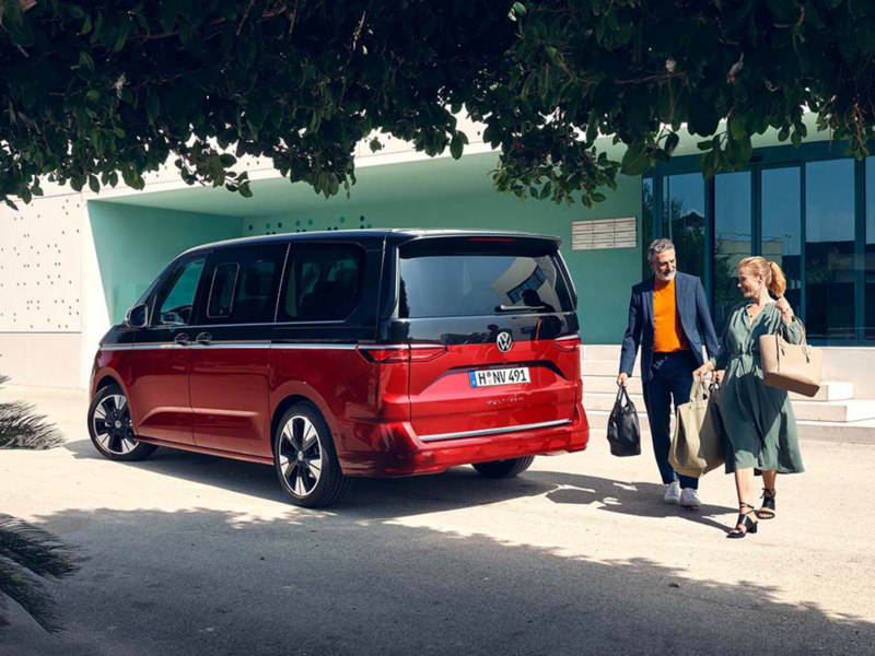 Dos personas acercándose a su Vehículo Seminuevo de Volkswagen Approved enmarcado entre árboles