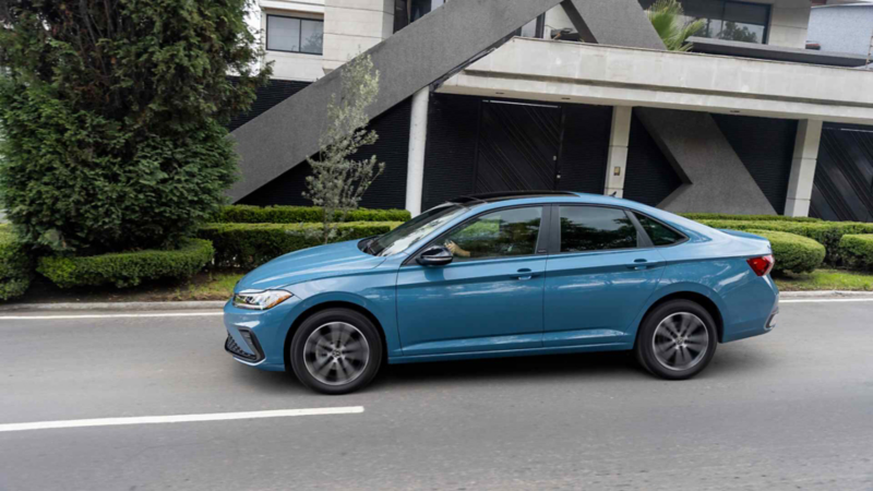 Volkswagen Jetta. Vista lateral de auto sedán de color azul en movimiento por la ciudad.
