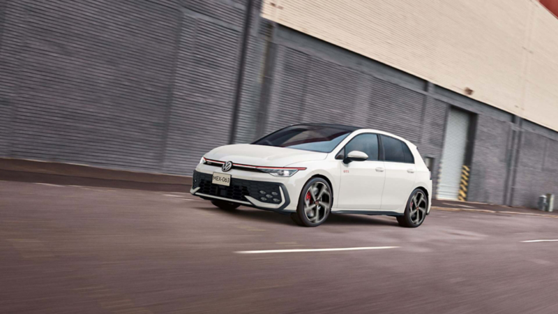 Golf GTI 2026 circula cerca de edificios de concreto. 