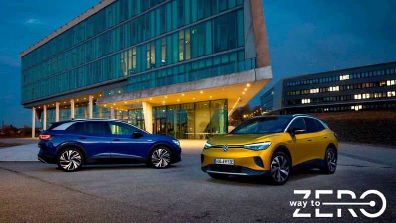 Camionetas SUV eléctricas de Volkswagen, en colores azul y amarillo, afuera de un edificio moderno.