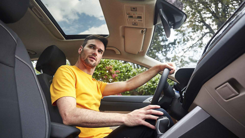 Conductor de Volkswagen en asiento mira por la ventana de copiloto.