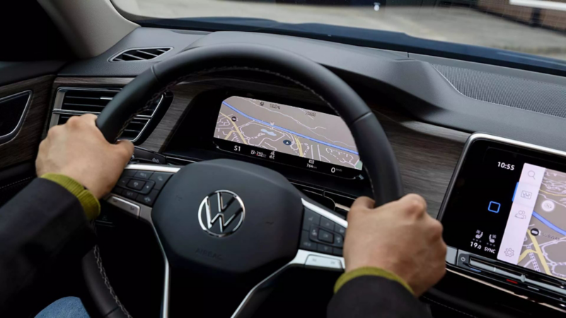 Conductor usa volante y pantalla digital de navegación en Volkswagen con sistema Digital Cockpit.