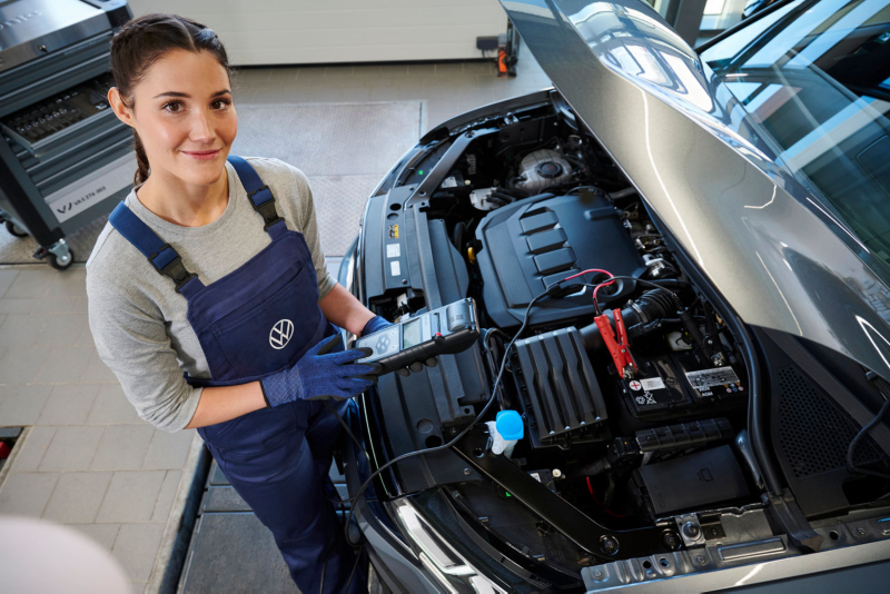 Une technicienne vérifie la batterie d'un véhicule utilitaire