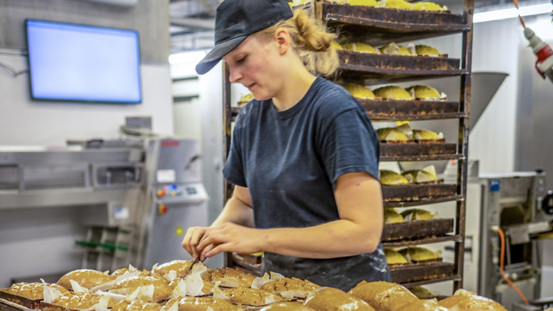Eine Frau bereitet Brötchen auf einem Blech auf