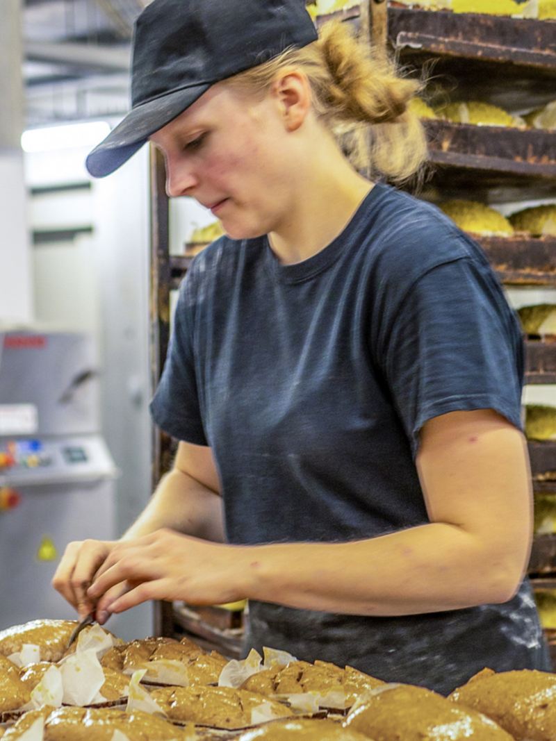 Une femme prépare des petits pains sur une plaque de cuisson