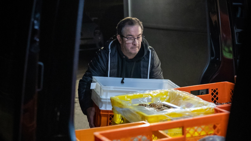 Ein Mann nimmt die frischen Backwaren aus dem e-Transporter