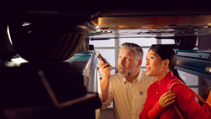 Un technicien Volkswagen se trouvant sous le véhicule, explique le fonctionnement des batteries d'une ID,