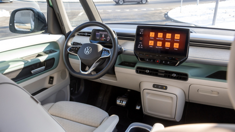 Abitacolo di un’auto elettrica Volkswagen con volante, quadro strumenti digitale e grande schermo touch sulla plancia.