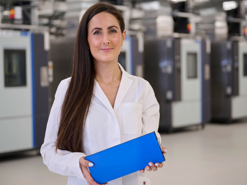Woman standing inside factory holding clipboard
