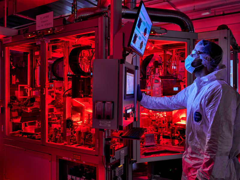 Man working in red-lit factory looking at screen