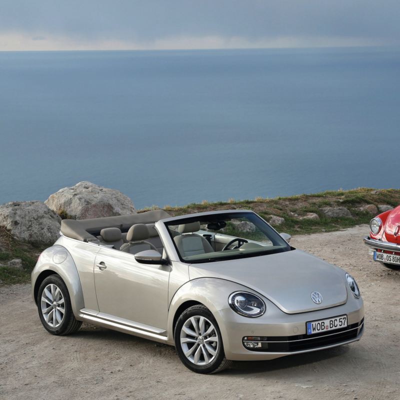 Autos Beetle en color gris platino y Vocho VW rojo tornado estacionados frente a playa