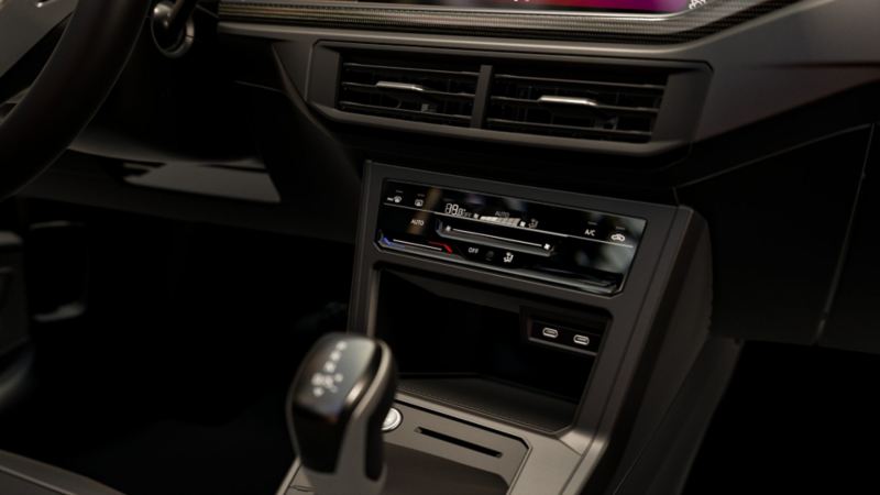 Interior de un auto Volkswagen con ventilas, panel de control de aire acondicionado y palanca de velocidades.