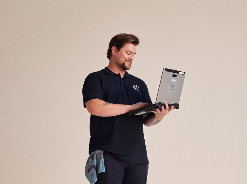 A Volkswagen service employee using a laptop on a plain background