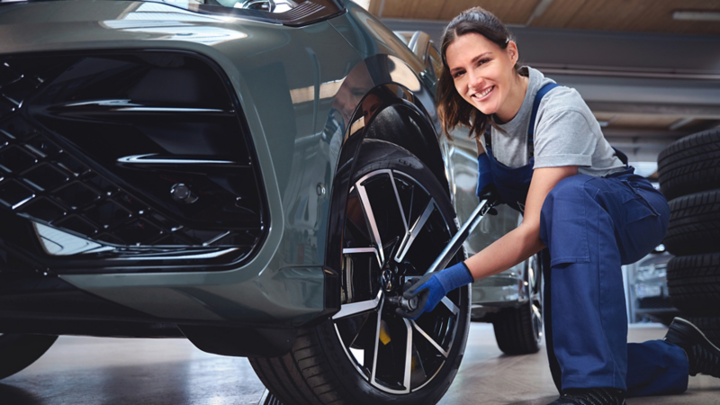 Volkswagen ID.7 vor einem Haus mit Wallbox geparkt, ein Paar spaziert daneben durch die Einfahrt im Grünen.