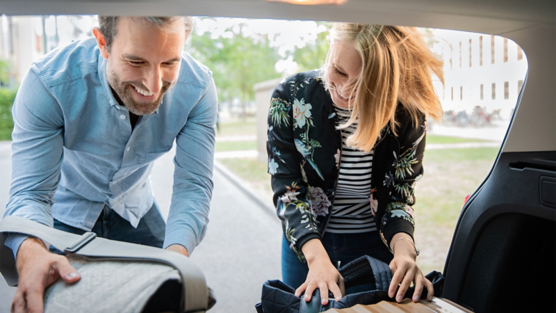 A woman and a man stowing their bags in the Volkswagen luggage compartment