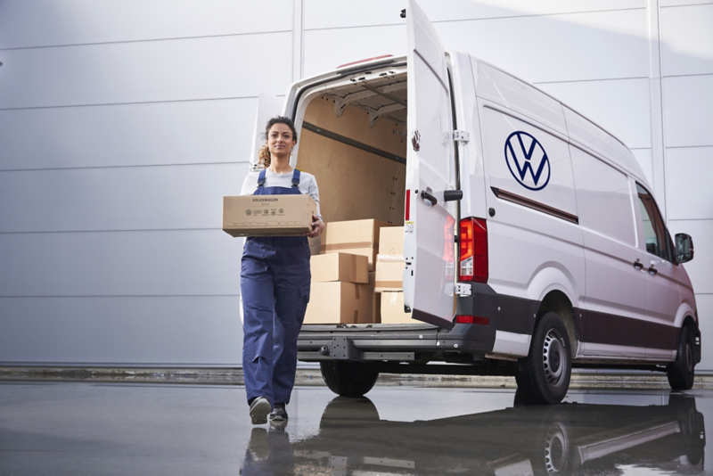 Pracownica przenosząca kartony z białego Volkswagena Craftera w wersji furgon podczas pracy