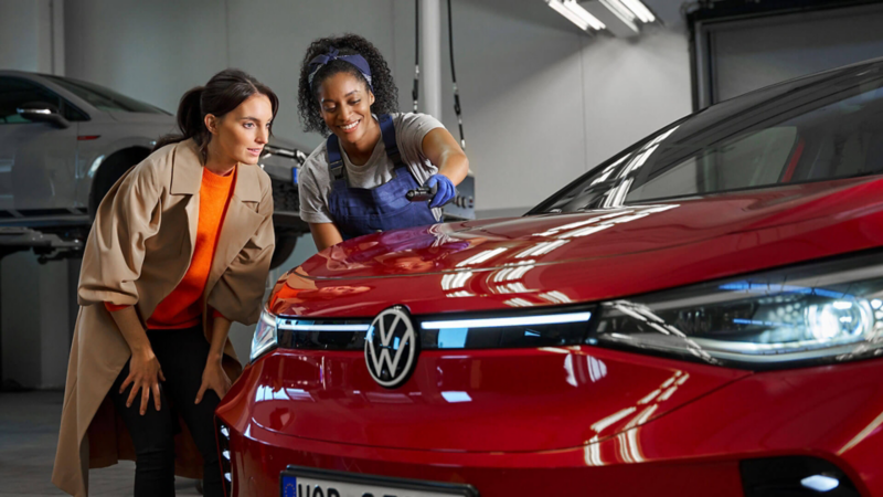 Une femme et une technicienne Volkswagen inspectent le capot d'une ID.