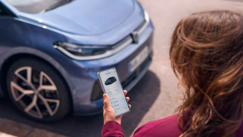 Une femme utilise son smartphone devant une ID.3 Neo.