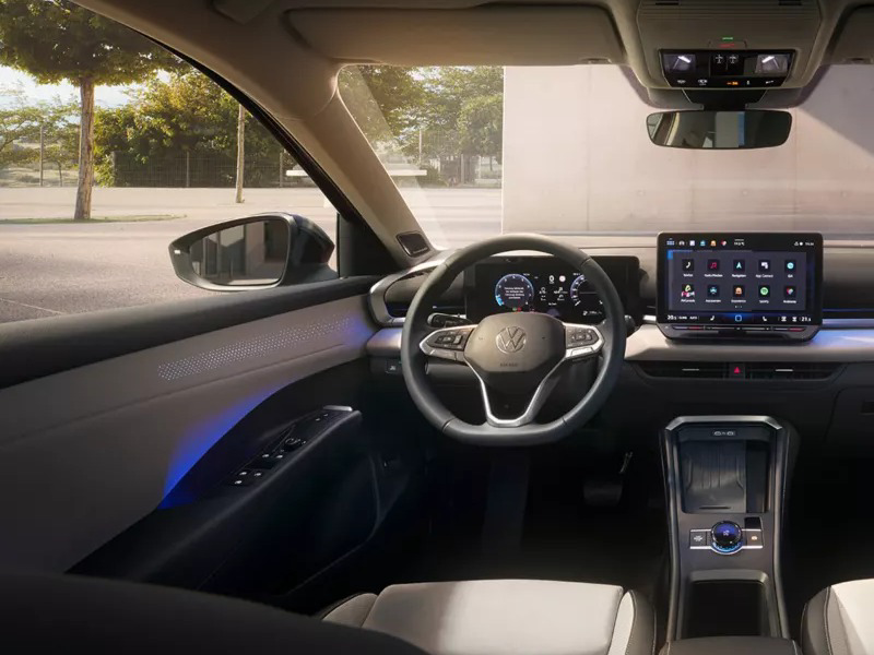 Interior view of a Volkswagen car showing the steering wheel, digital dashboard, and central infotainment screen with ambient blue door lighting.