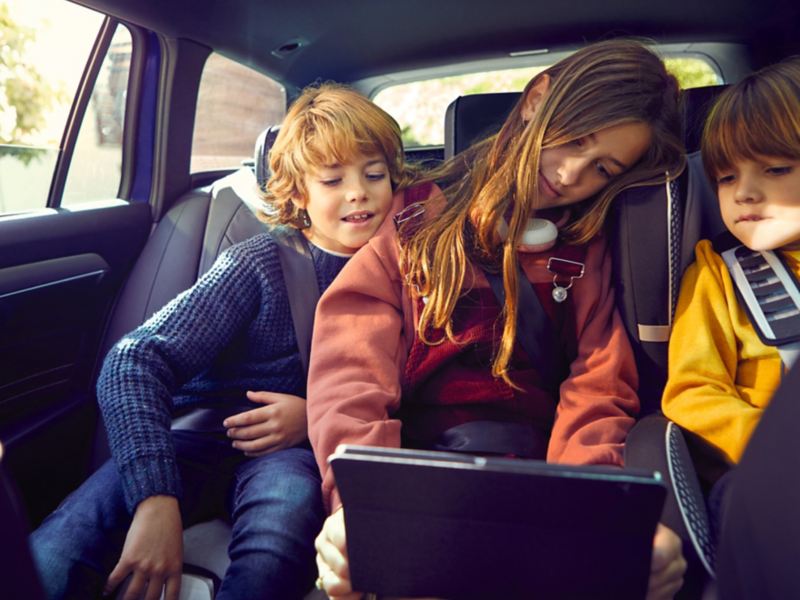 Niños en el asiento trasero del vehículo VW usando wifi.