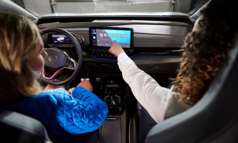 Woman using infotainment system in VW vehicle.