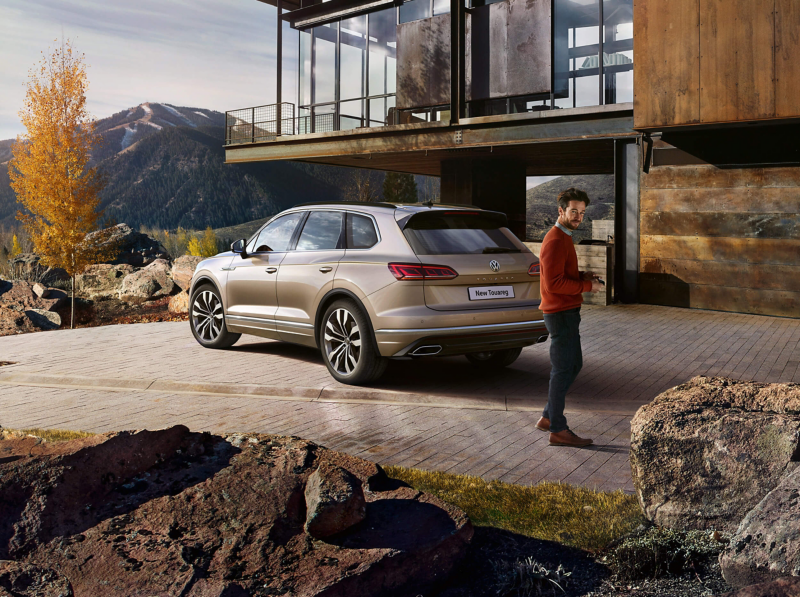 A bronze Volkswagen Touareg outside a house in the mountains.