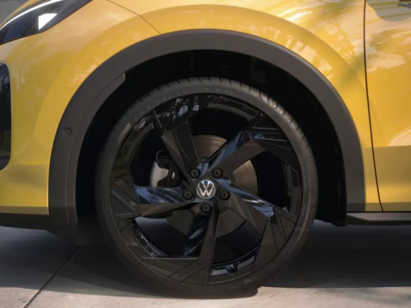 Close-up of the glossy black sporty wheel and tire of a yellow Volkswagen car.
