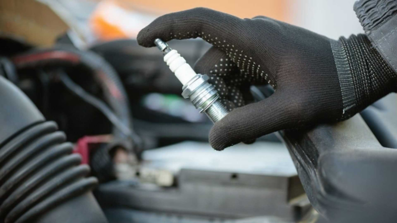 Mano de técnico de Volkswagen sostiene una bujía. 
