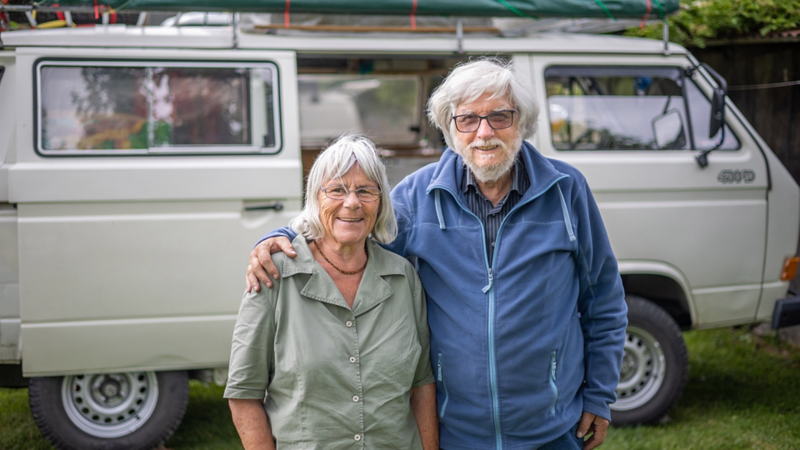 Ein älteres Paar steht vor einem VW Bus T3 Syncro.