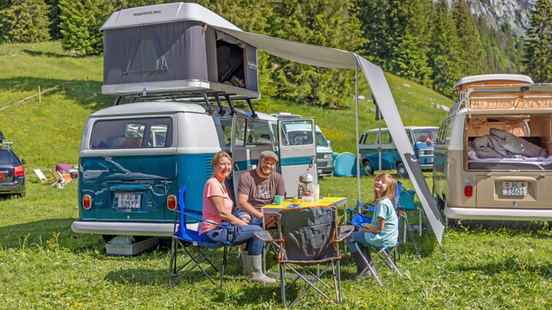 Eine Familie sitzt vor ihrem VW Bus T1.