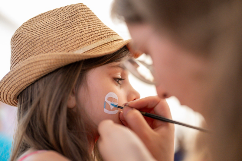 A girl is painted with the VW Bus Festival logo.
