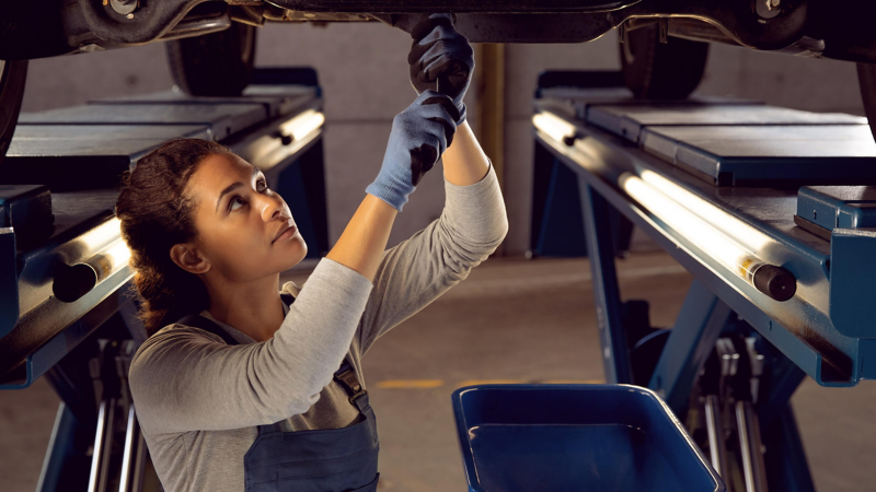 A service mechanic making repairs beneath a Volkswagen van