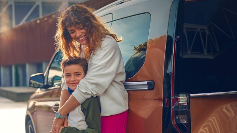 A mother and son leaning against a Caddy van