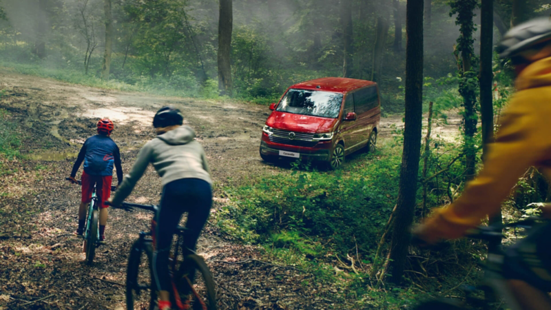 Photo showing a group of cyclists cycling toward a parked VW camper van. 
