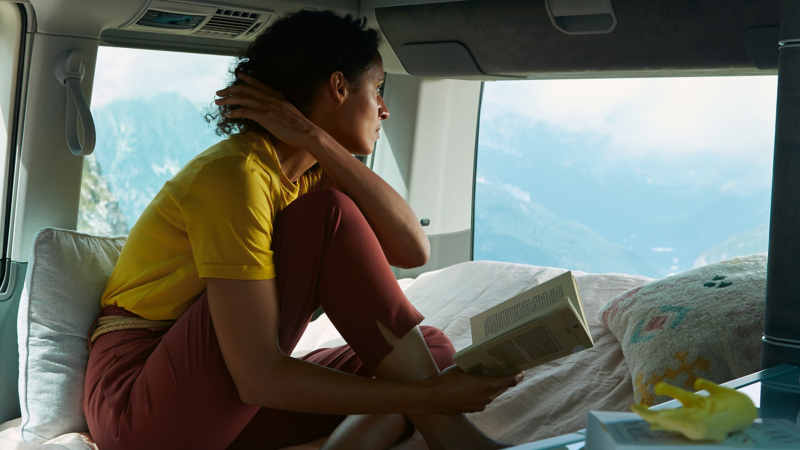 Photo of a woman relaxing in a VW motorhome. 