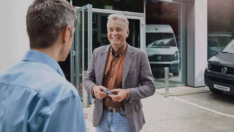 Two people talking while standing outside of a VW Van Centre. 