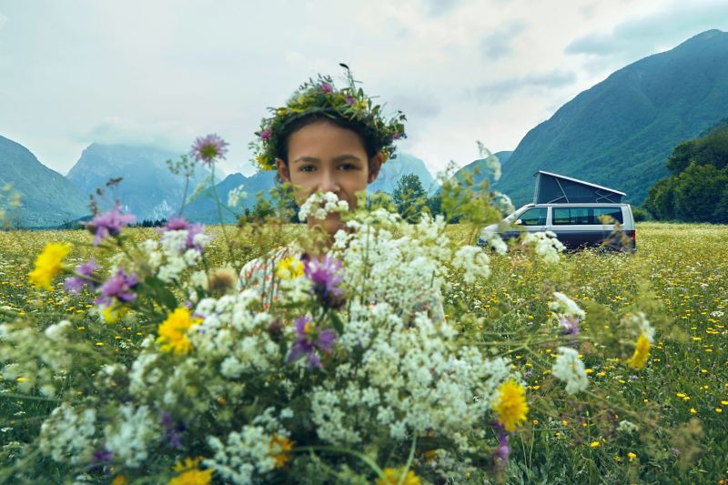 Dziecko z wieńcem z kwiatów na polu.