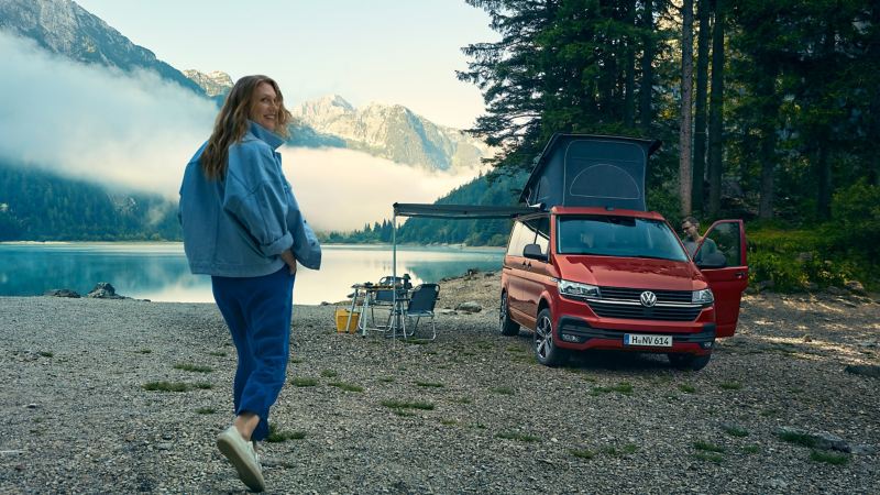 Ein VW California parkt an einem See mit komfortabler Campingausstattung.