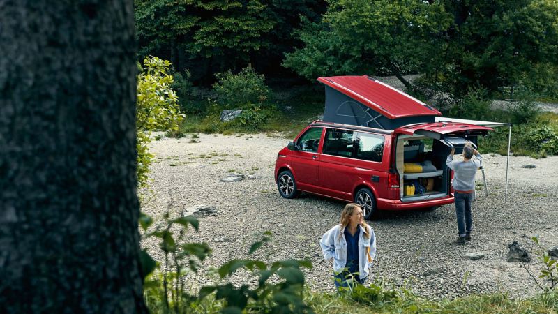 Photo of a couple setting up a camp next to their parked California. 