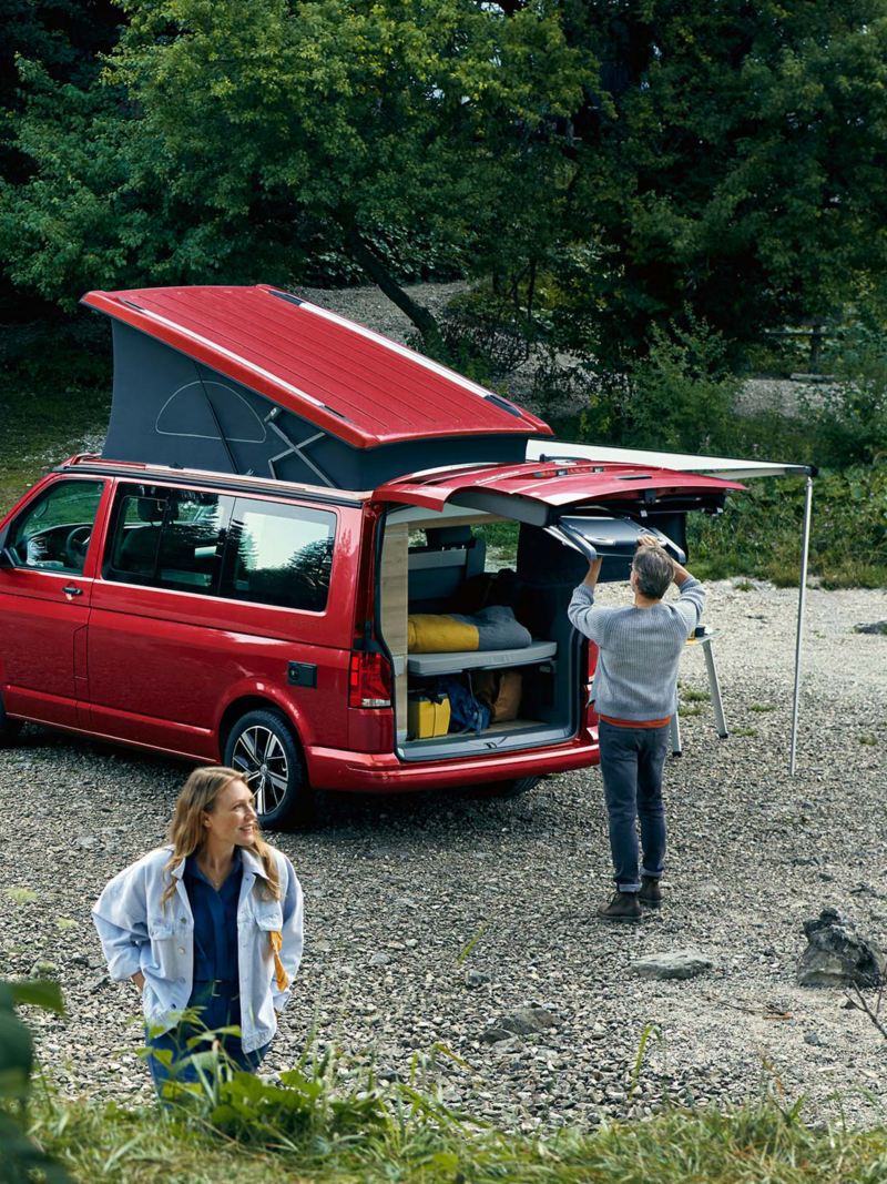 Photo of a couple setting up a camp next to their parked California. 