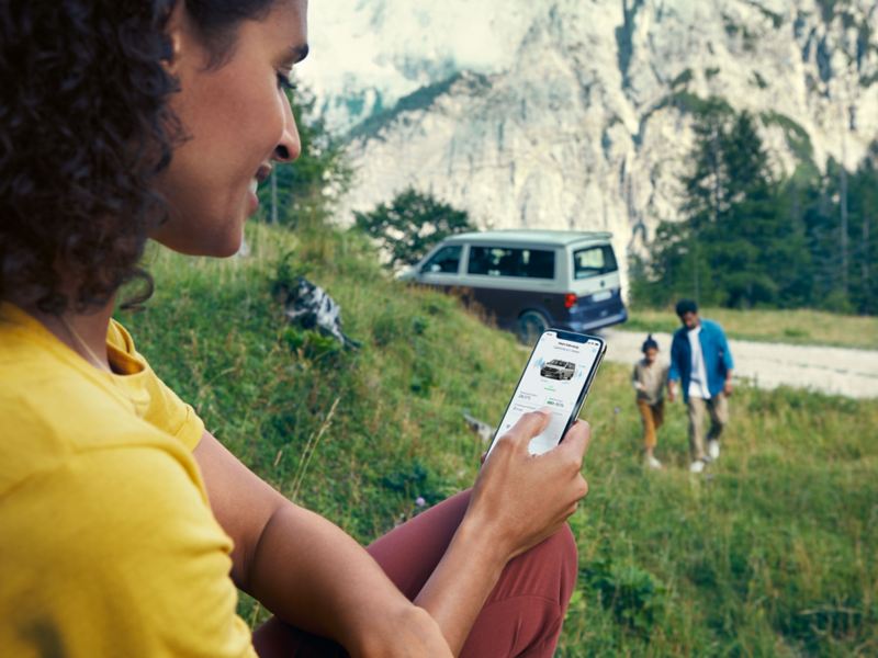 Eine Person sitzt auf einem Hügel mit einem Smartphone in der Hand mit der California Fernsteuerung.