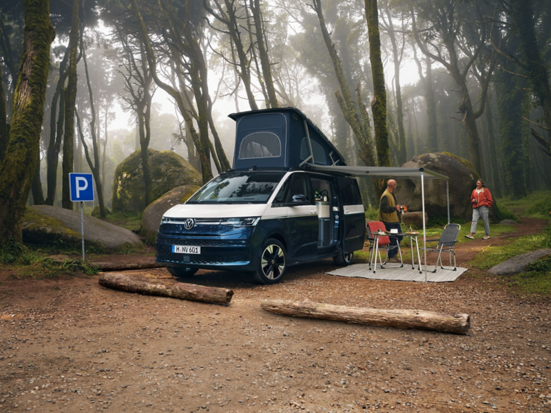 VW California bleu et blanc ouvert avec hauvent et table de camping