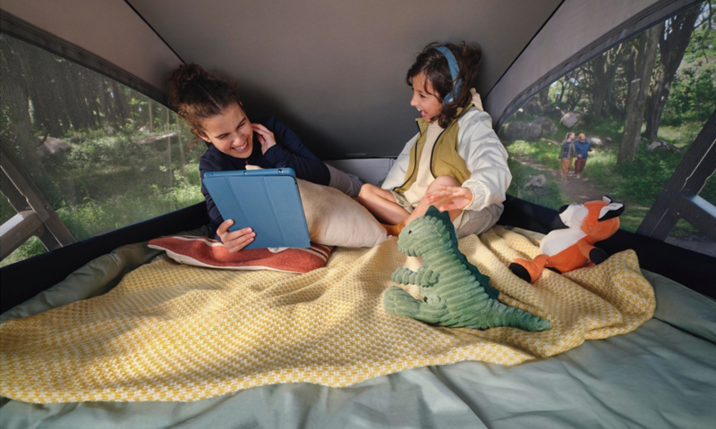 Zwei Kinder spielen im aufgestellten Dachzelt eines VW California.