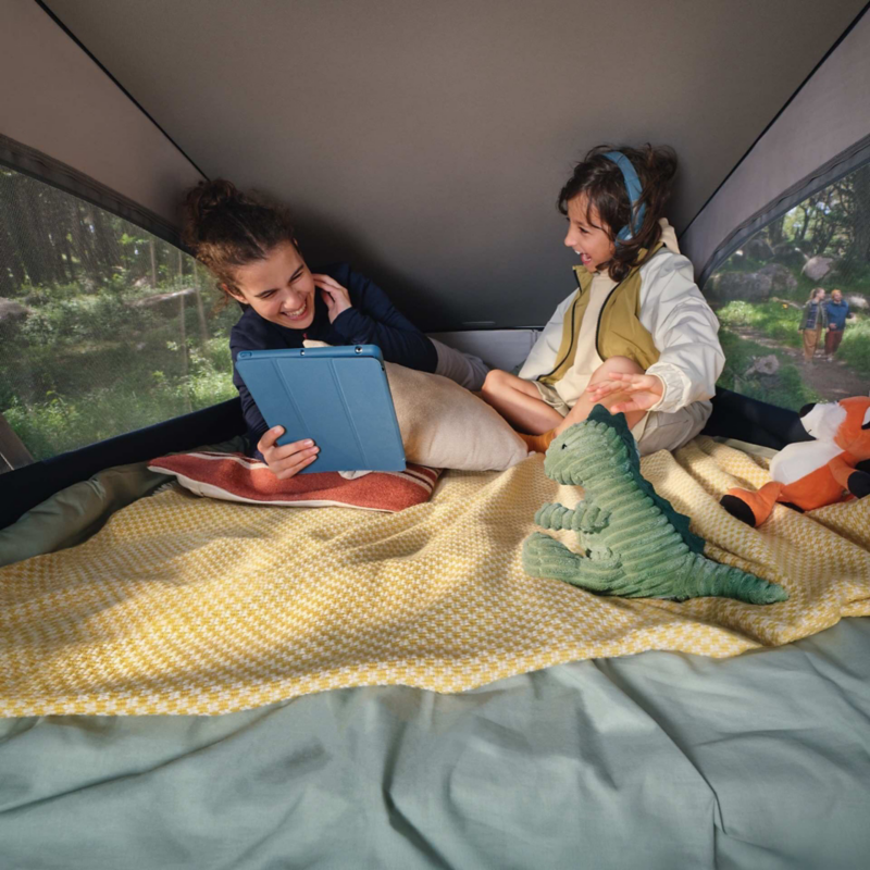 Two children sat inside a California listening to music and using a tablet.