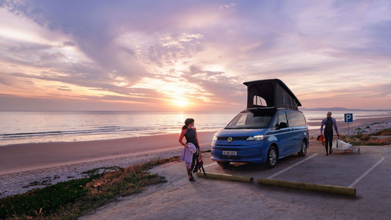 Le Volkswagen California sur une plage avec des surfeurs.