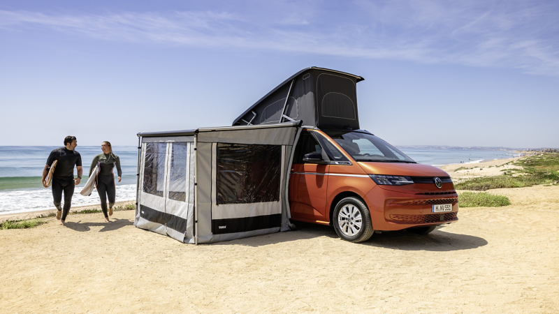 Ein VW California Parkt am Strand mit aufgebautem Anbauzelt und Schlafzelt.