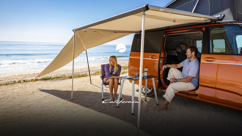 Ett par sitter under markisen vid sin VW California på en strand i Kroatien.