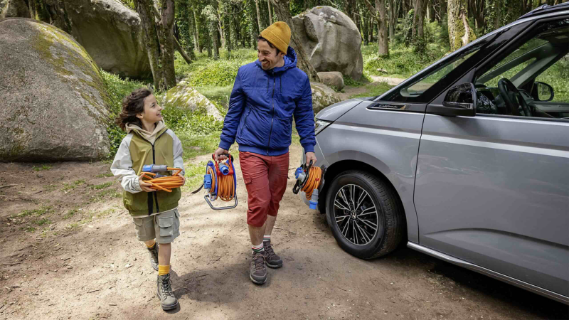 A man and a girl walking past a parked California. 